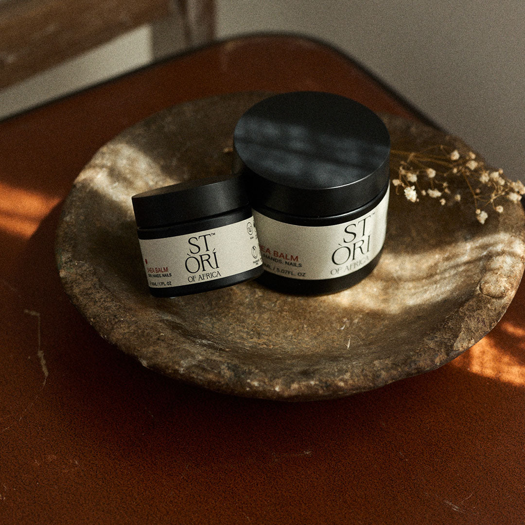 One 50ml and one 150ml Stori of Africa Shea Balm Essential Bundle on a wooden bowl.